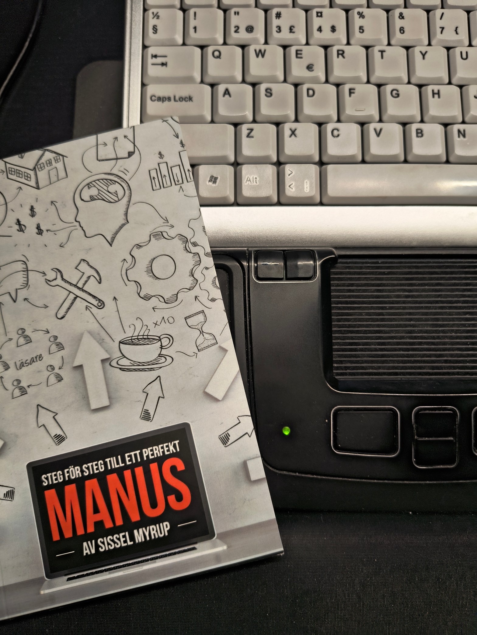 Bild på redigeringsbok Steg för steg till ett perfekt manus av Sissel Myrup liggandes på ett tangentbord